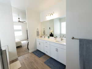 Full bath with ensuite bath, double vanity, and light wood-style flooring