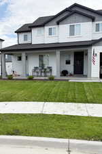 View of front of house with a porch, board and batten siding, a front yard, and roof with shingles