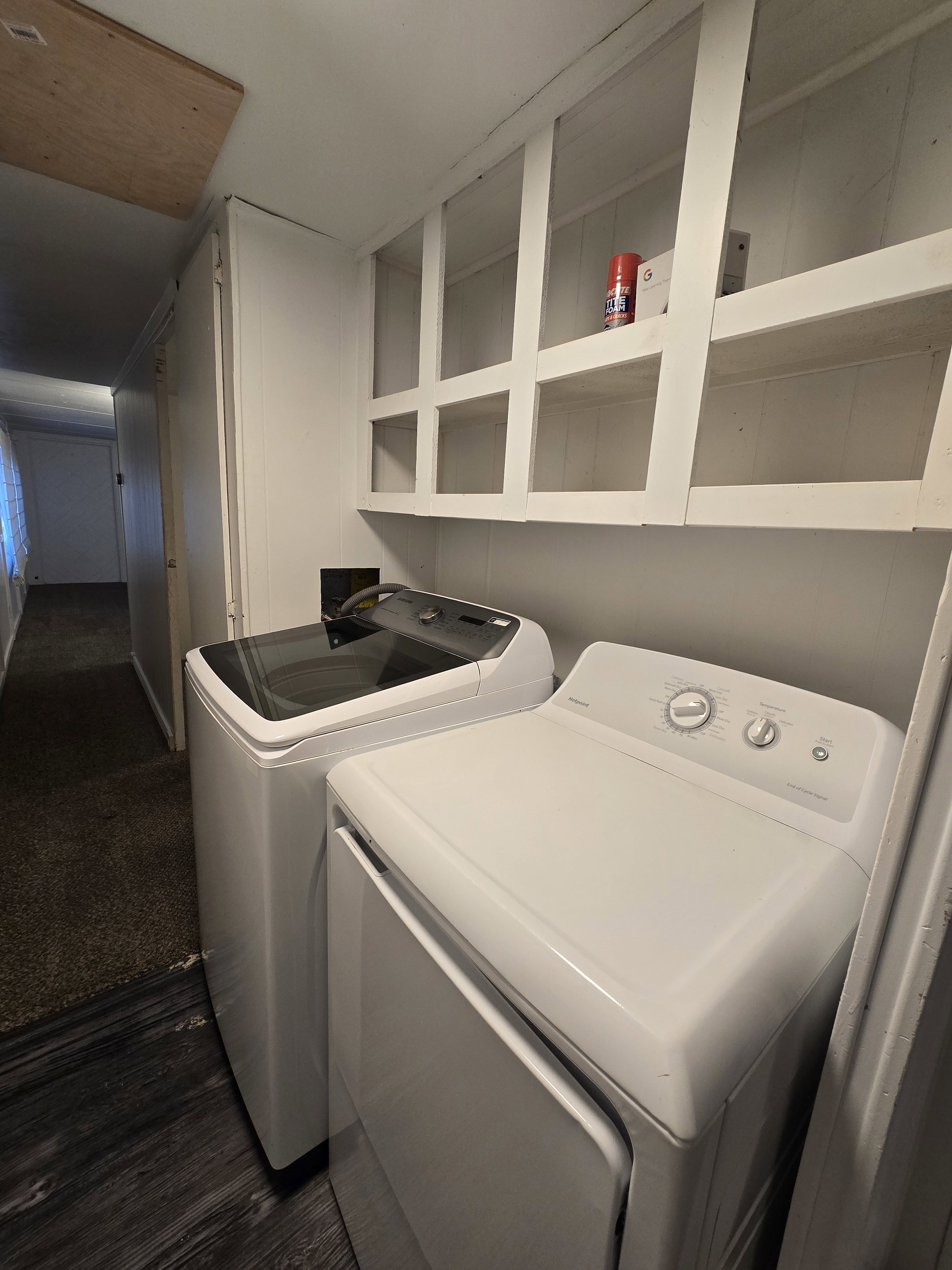 Laundry area featuring open shelving, wood-finish flooring, and white paneled walls