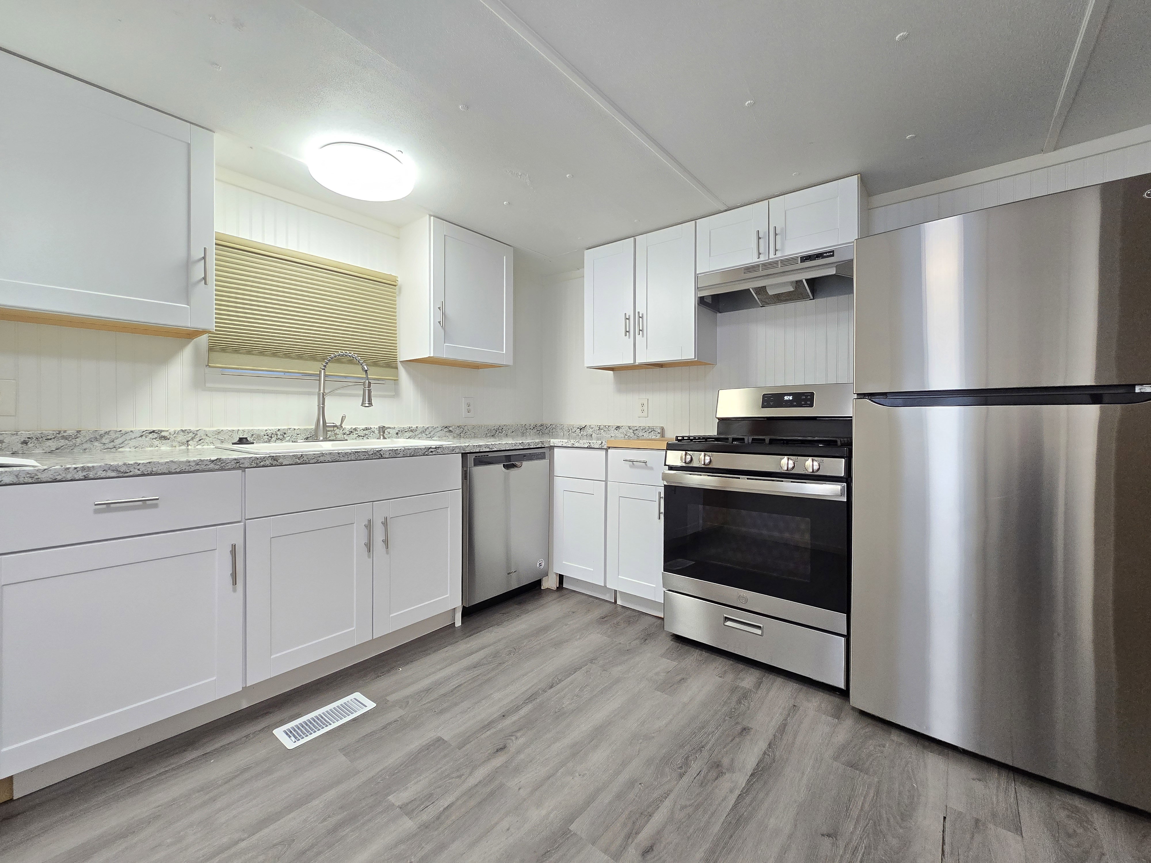 Kitchen featuring wood-finish flooring, white cabinetry, a stainless steel gas range, a stainless steel refrigerator, and a stainless steel dishwasher