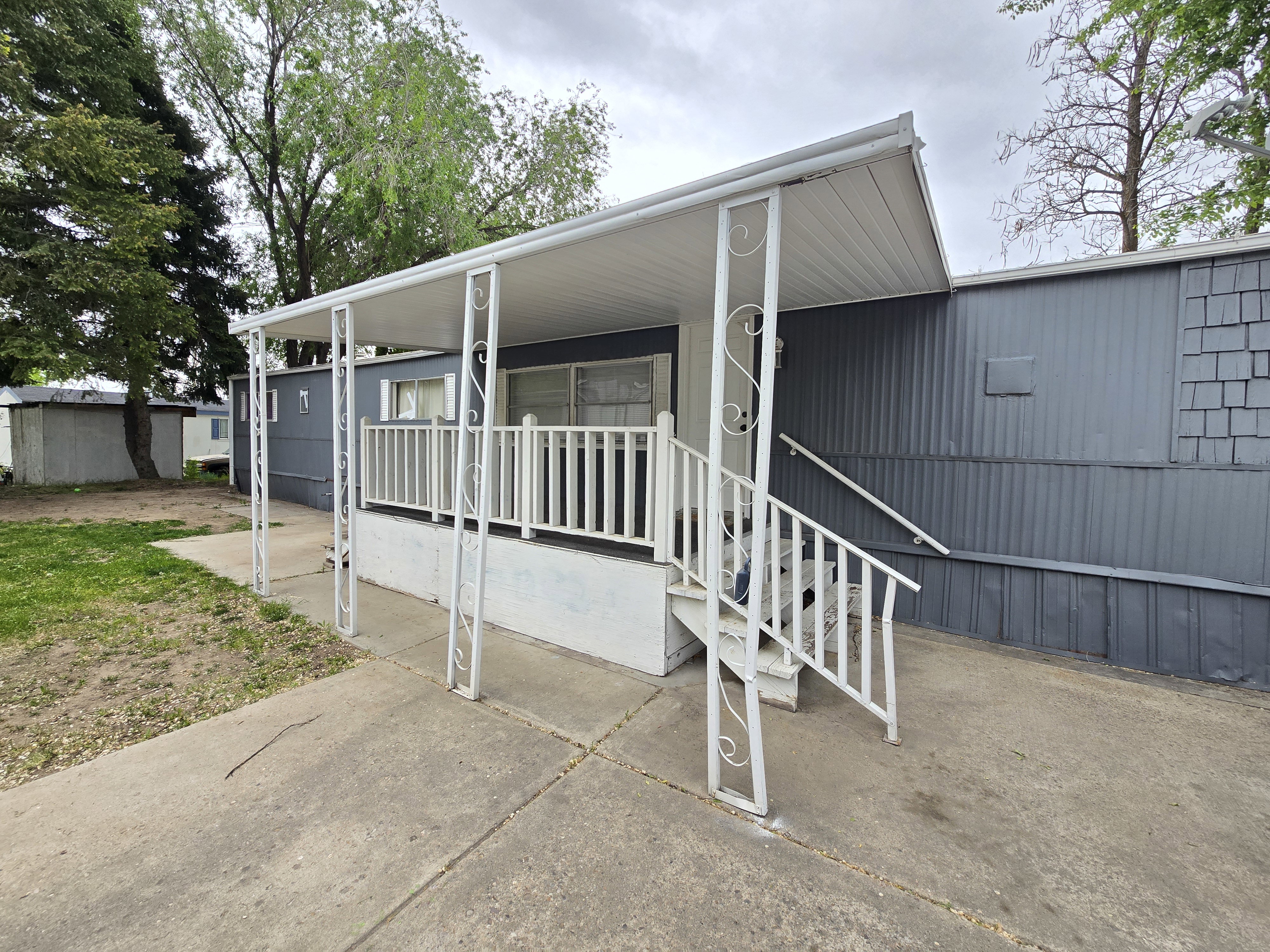 Covered porch entry featuring white railings and decorative metal columns