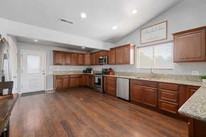 Kitchen with stainless steel appliances, light stone countertops, dark wood finished floors, wood finish cabinets, and recessed lighting