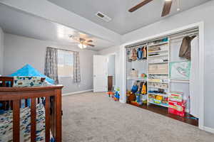 Bedroom with dark colored carpet, ceiling fan, a crib, and a closet