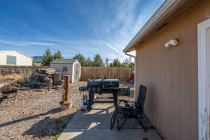 Fenced backyard featuring a storage shed, a patio, and a grill
