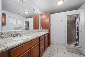 Bathroom featuring double vanity, a stall shower, and light tile patterned floors