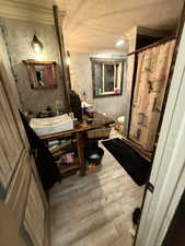 Full bathroom with light wood-style flooring, vanity, and a shower with curtain