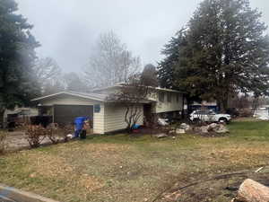 View of side of home featuring a lawn and an attached garage