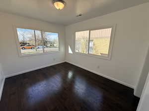 Unfurnished room featuring dark wood finished floors and baseboards