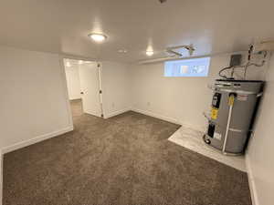 Below grade area with water heater and dark colored carpet