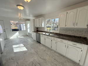 Kitchen featuring white cabinetry, decorative backsplash, plenty of natural light, and stainless steel dishwasher