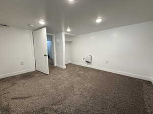 Finished below grade area with baseboards and dark colored carpet