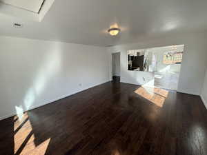 Unfurnished living room featuring dark wood-style flooring