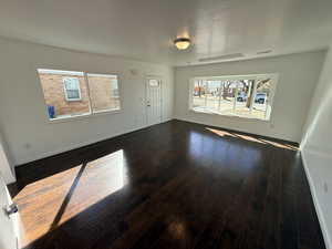 Unfurnished living room with baseboards and dark wood-style flooring
