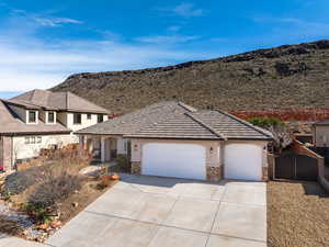 View of front of house featuring a garage, concrete driveway, stone siding, stucco siding, and a gate