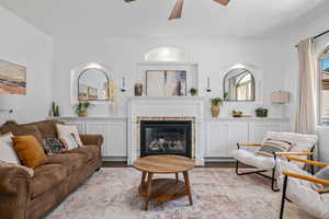 Living room with a glass covered fireplace, a ceiling fan, and wood finished floors