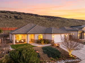 View of front of home with an attached garage, driveway, stone siding, stucco siding, and a tiled roof