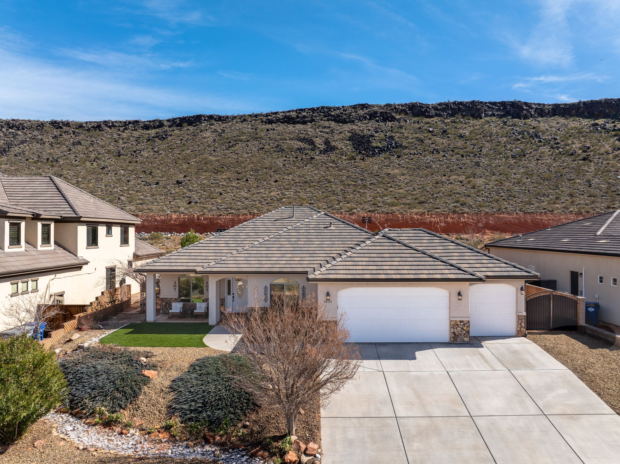 View of front facade featuring a garage, concrete driveway, stucco siding, stone siding, and a tile roof