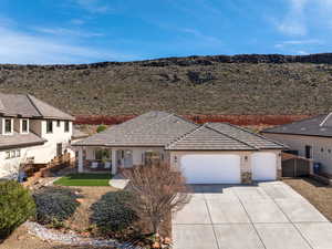 View of front facade featuring a garage, concrete driveway, stucco siding, stone siding, and a tile roof