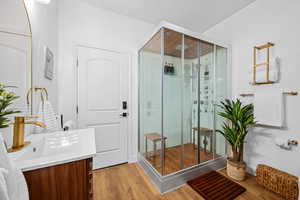 Full bathroom with a stall shower, vanity, and light wood-type flooring