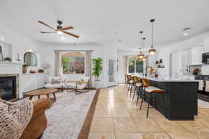 Living area with a ceiling fan, a brick fireplace, light tile patterned flooring, and recessed lighting