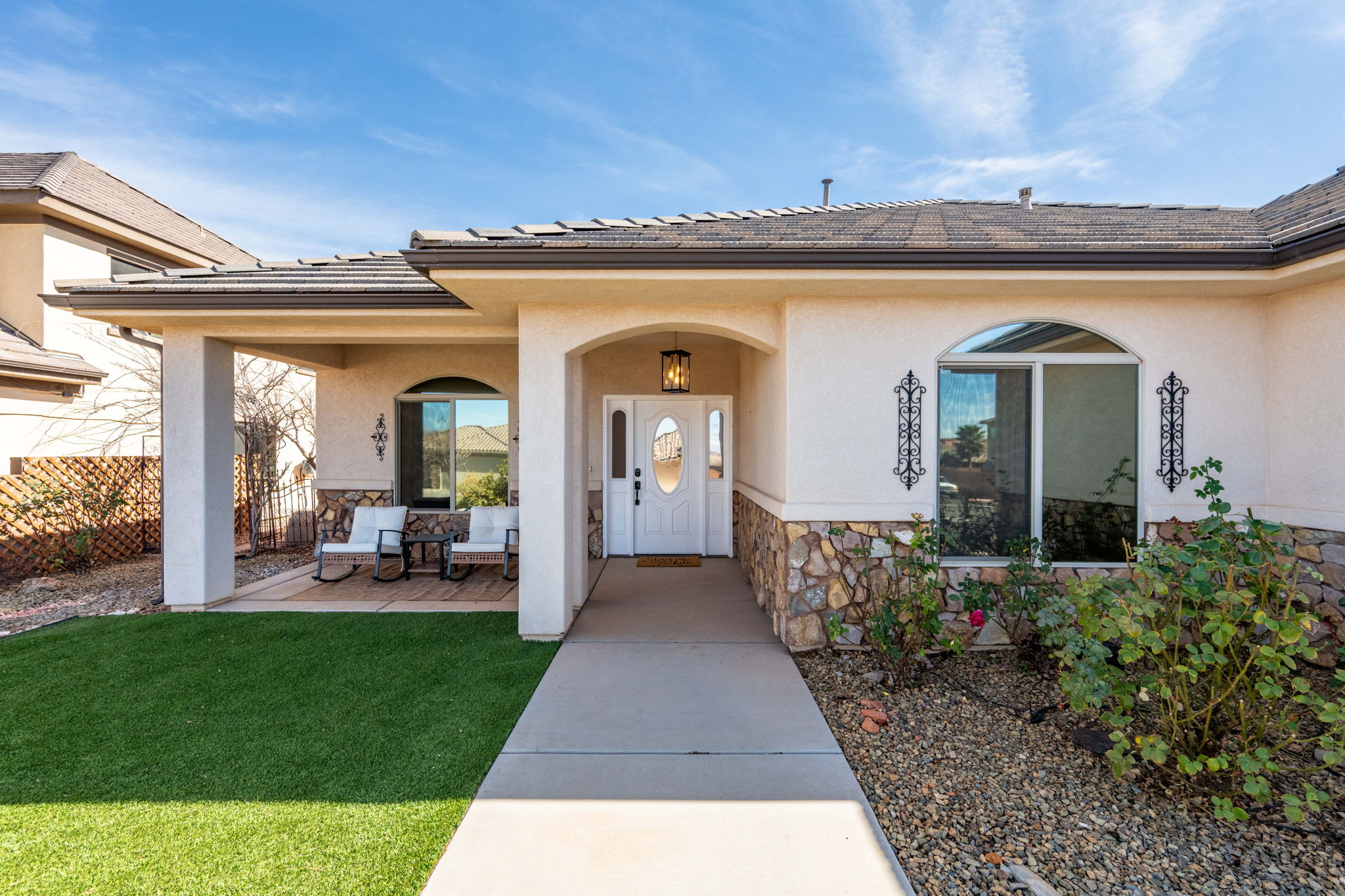 Property entrance featuring stone siding, stucco siding, covered porch, and a tiled roof