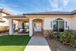 Property entrance featuring stone siding, stucco siding, covered porch, and a tiled roof