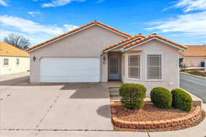 Mediterranean / spanish-style house featuring an attached garage, stucco siding, driveway, and a tiled roof