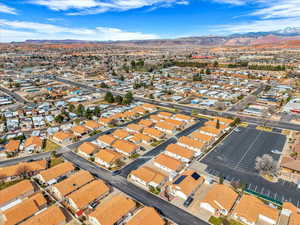 Aerial view of property and surrounding area featuring a mountainous background and nearby suburban area