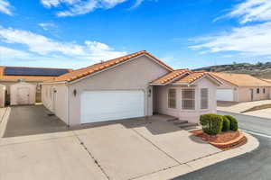 Mediterranean / spanish home featuring a storage unit, stucco siding, a garage, concrete driveway, and a tile roof