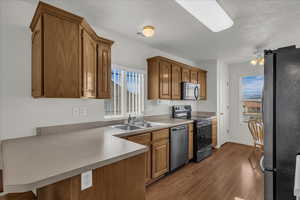 Kitchen featuring stainless steel appliances, a ceiling fan, light countertops, and wood finish cabinets