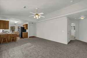 Living area featuring plenty of natural light, light carpet, and a ceiling fan