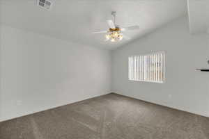 Carpeted spare room with ceiling fan and vaulted ceiling