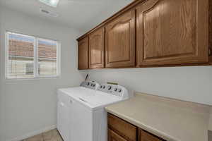 Laundry room with washing machine and dryer, cabinet space, and light tile patterned floors
