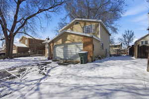 View of snow covered exterior featuring a garage and brick siding