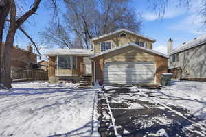 View of front facade with brick siding, driveway, and an attached garage