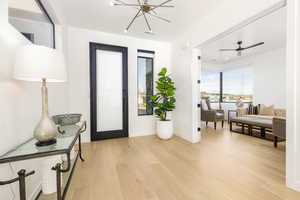 Entrance foyer with light wood-style floors, suspended lighting, and a ceiling fan