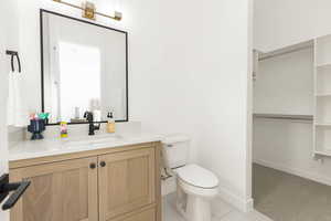Bathroom with a spacious closet, vanity, light tile patterned floors, and light colored carpet