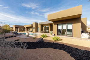Rear view of property featuring stucco siding, an outdoor pool, and a patio area