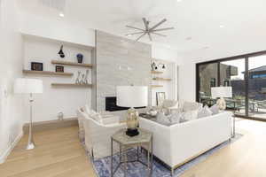 Living room featuring a fireplace, light wood-style flooring, ceiling fan, and recessed lighting