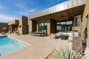 Rear view of house with a patio area, a ceiling fan, an outdoor pool, and stucco siding