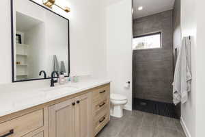 Full bath featuring vanity, walk in shower, recessed lighting, and light tile patterned floors