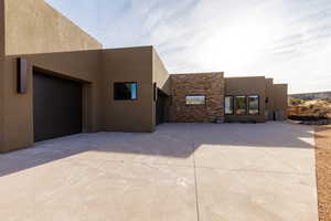 View of side of property featuring stone siding, stucco siding, and driveway