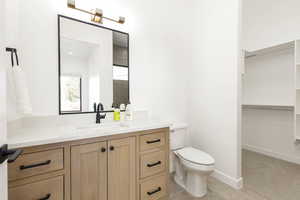 Full bathroom featuring vanity, a spacious closet, and light tile patterned flooring