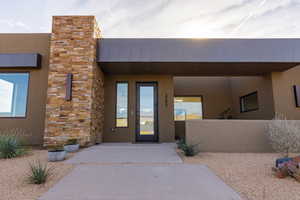 Doorway to property featuring stucco siding, stone siding, and a porch
