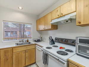 Kitchen with white appliances, light countertops, light tile patterned floors, light wood finish cabinetry, and recessed lighting