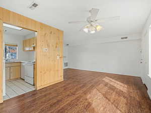 Unfurnished living room featuring light wood-style flooring, a ceiling fan, and wooden walls