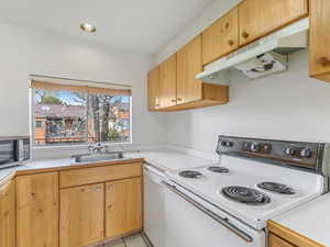 Kitchen featuring white appliances, light countertops, light wood finish cabinetry, light tile patterned flooring, and recessed lighting