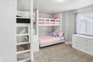 Bedroom featuring light colored carpet and a textured ceiling