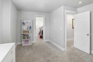 Unfurnished bedroom with light carpet and a spacious closet
