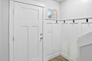 Doorway to outside featuring wood finished floors and wainscoting